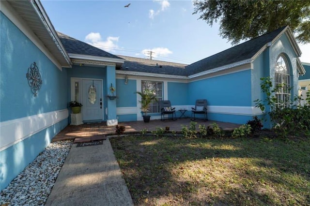 entrance to property featuring a patio and a yard