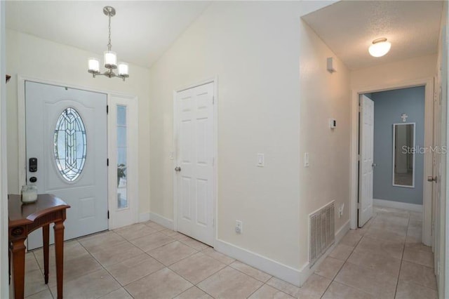 tiled entrance foyer featuring vaulted ceiling and an inviting chandelier