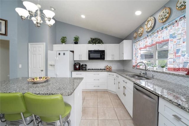 kitchen with sink, light tile patterned floors, appliances with stainless steel finishes, white cabinetry, and decorative light fixtures