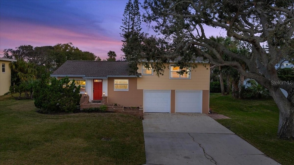 tri-level home featuring a garage, driveway, and a lawn