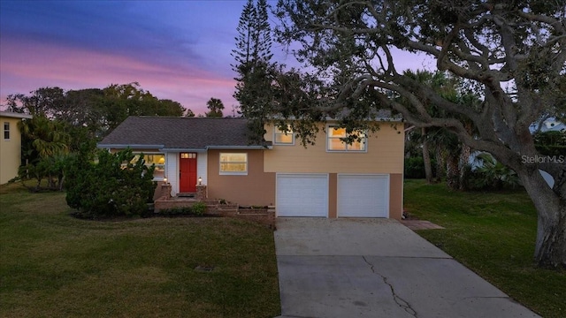 tri-level home featuring a garage, driveway, and a lawn