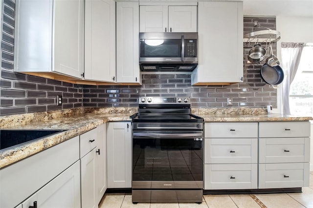 kitchen with tasteful backsplash, light tile patterned floors, stainless steel appliances, light stone countertops, and white cabinets