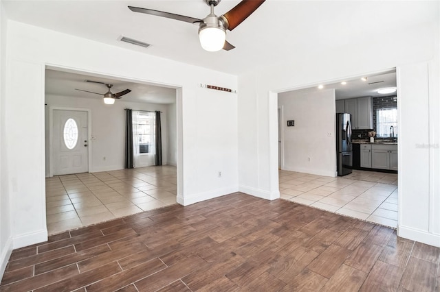 unfurnished living room featuring sink, ceiling fan, and light wood-type flooring