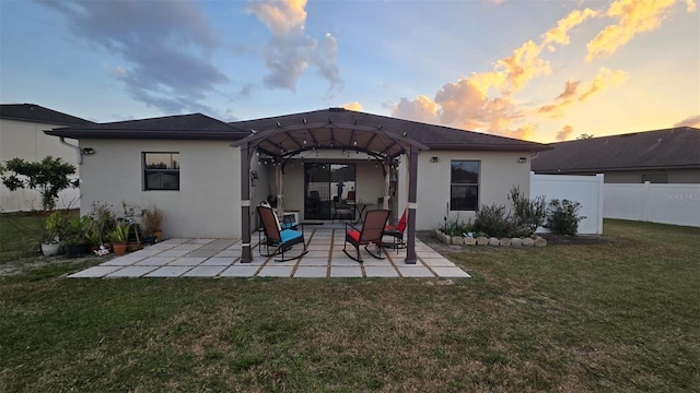 back house at dusk featuring a yard and a patio area