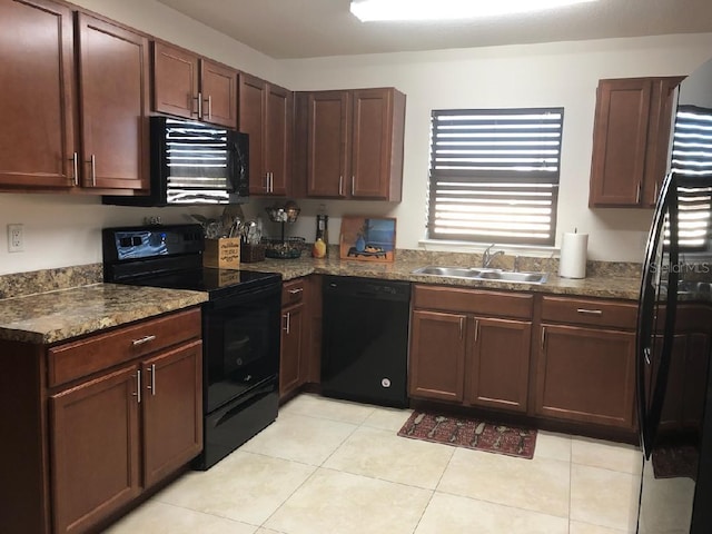 kitchen with sink, light tile patterned floors, dark stone countertops, dark brown cabinetry, and black appliances