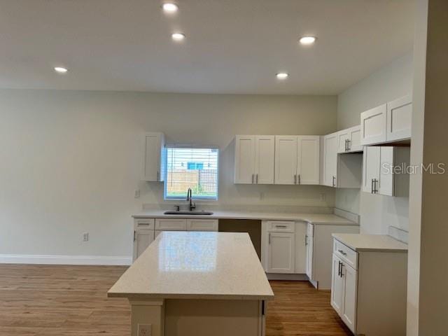 kitchen with a kitchen island, sink, white cabinets, and light hardwood / wood-style floors