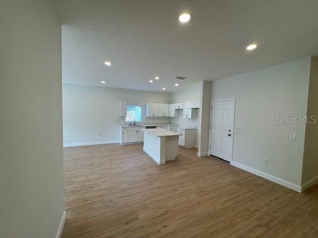 kitchen with sink, light hardwood / wood-style flooring, a center island, and white cabinets