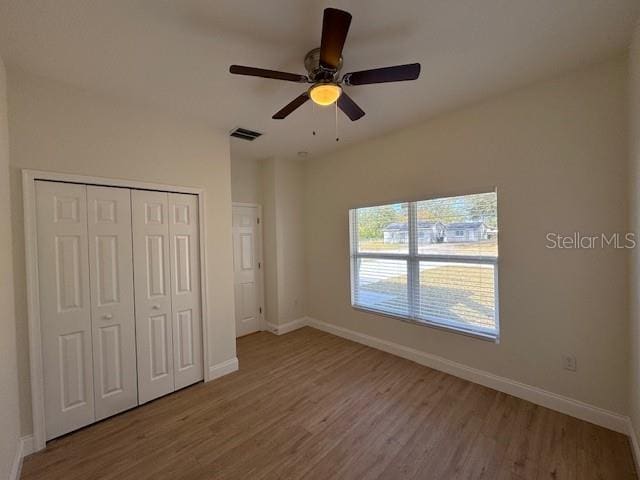 unfurnished bedroom featuring ceiling fan, light hardwood / wood-style floors, and a closet