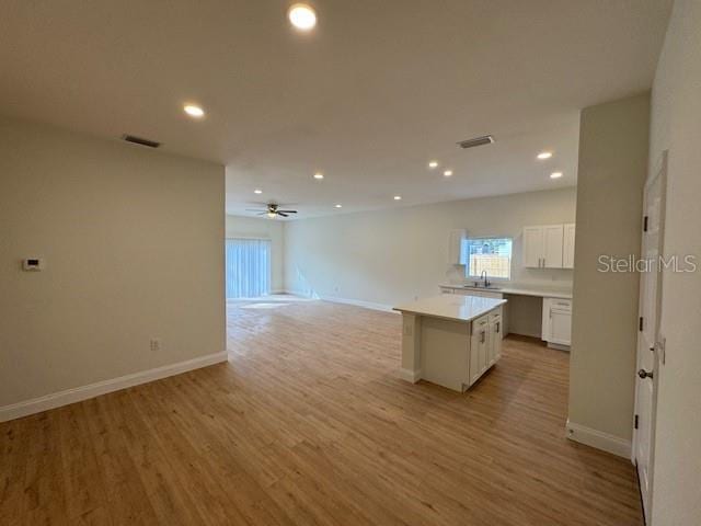 kitchen featuring sink, ceiling fan, white cabinetry, a center island, and light hardwood / wood-style floors