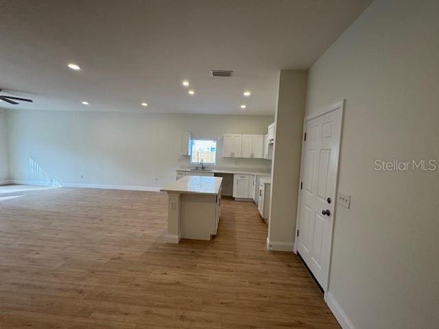 kitchen featuring a kitchen island, white cabinetry, sink, ceiling fan, and light hardwood / wood-style flooring