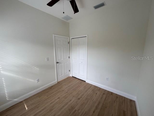 unfurnished bedroom with dark hardwood / wood-style floors, ceiling fan, and a closet