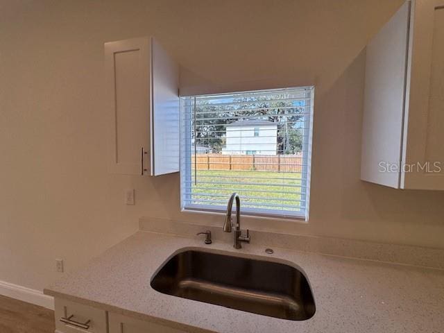 kitchen with light stone counters, sink, and white cabinets