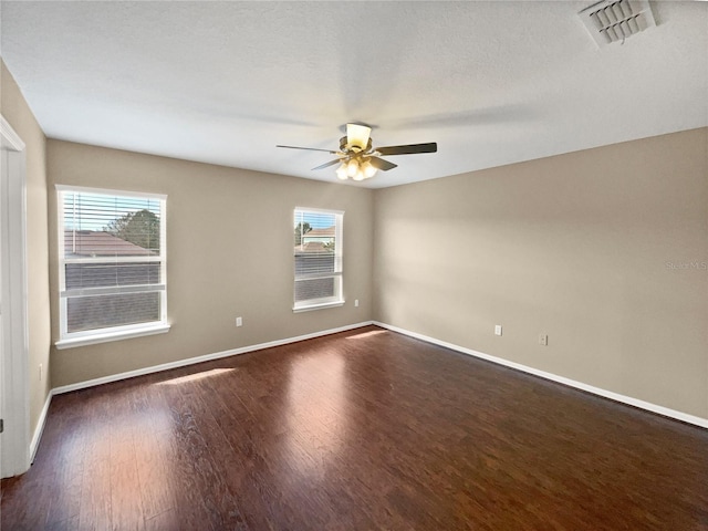 empty room with ceiling fan, a healthy amount of sunlight, and dark hardwood / wood-style flooring