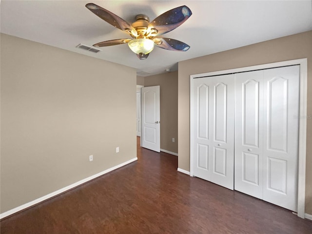 unfurnished bedroom featuring dark wood-type flooring, a closet, and ceiling fan
