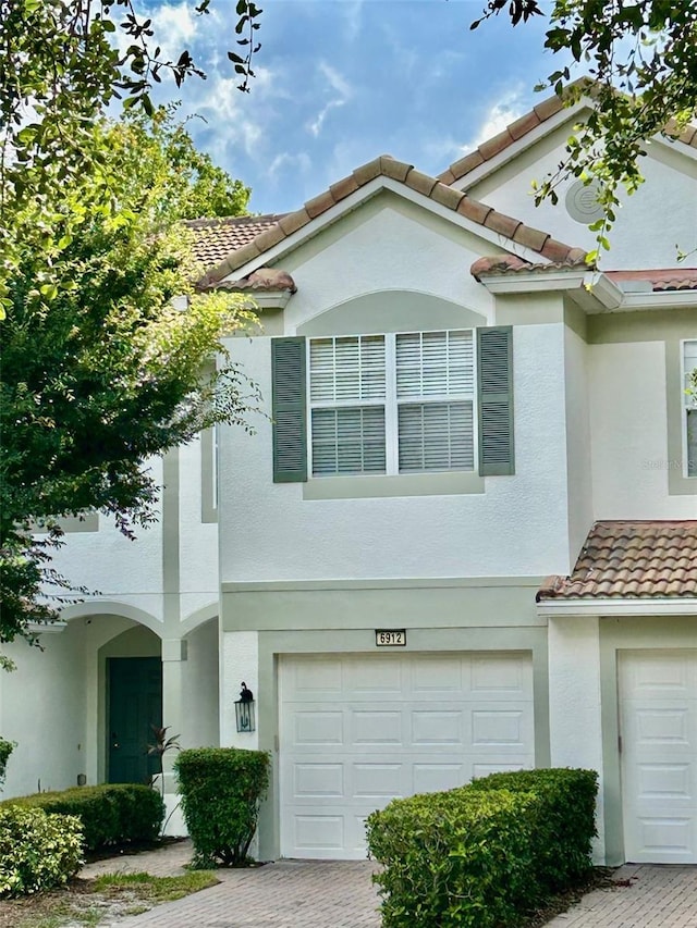 6912 Hochad Dr, Orlando, FL 32819 - multi unit property with an attached garage, decorative driveway, a tile roof, and stucco siding