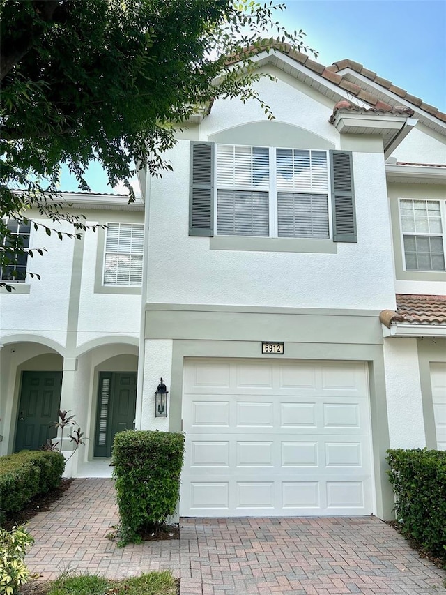 6912 Hochad Dr, Orlando, FL 32819 - multi unit property with stucco siding, a garage, decorative driveway, and a tiled roof
