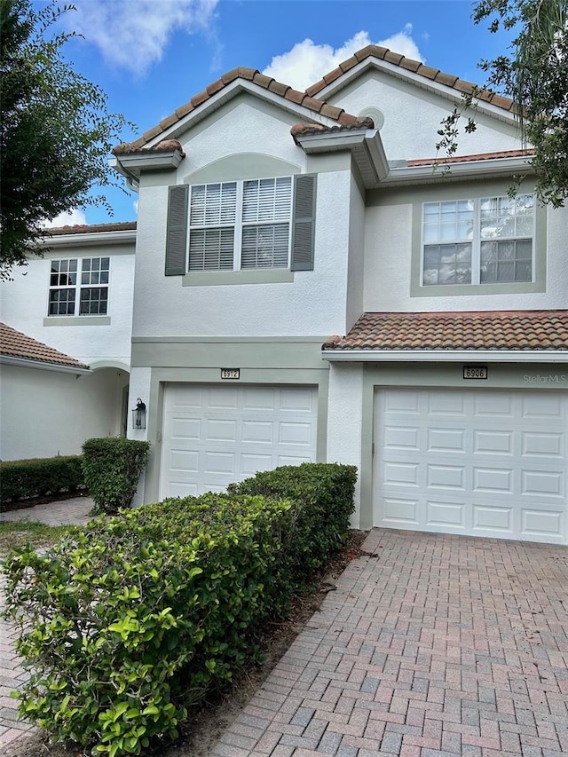 6912 Hochad Dr, Orlando, FL 32819 - view of front of house with a garage, stucco siding, decorative driveway, and a tiled roof