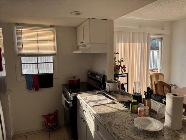 kitchen featuring light tile patterned flooring, white cabinetry, electric range oven, a textured ceiling, and light stone countertops