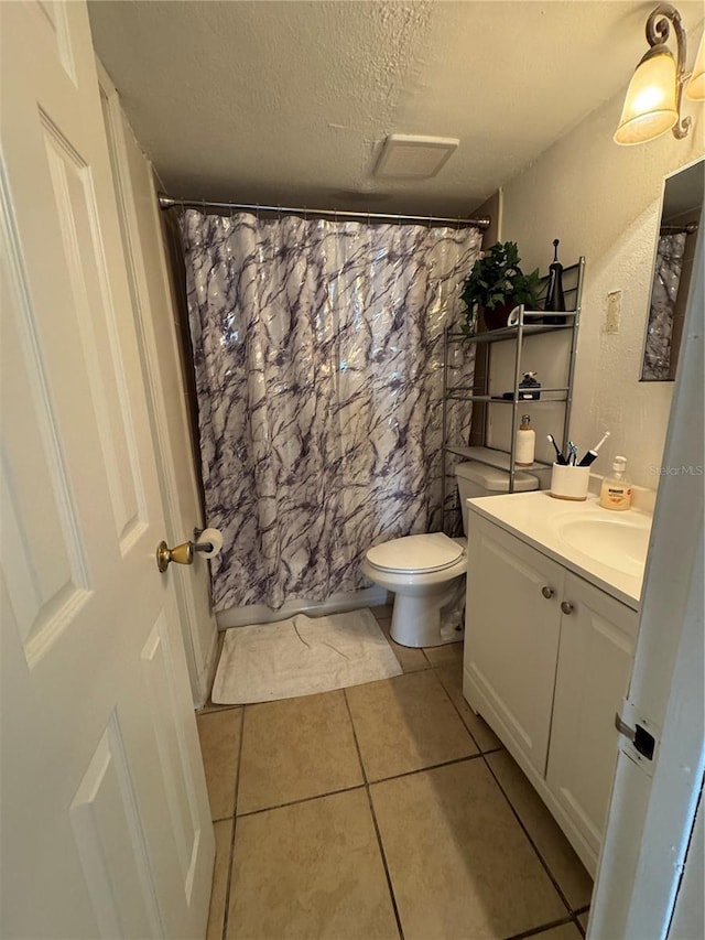 bathroom featuring tile patterned flooring, vanity, a textured ceiling, toilet, and walk in shower