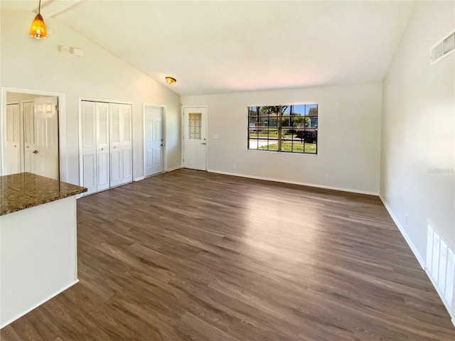 unfurnished living room featuring dark hardwood / wood-style flooring and vaulted ceiling with beams