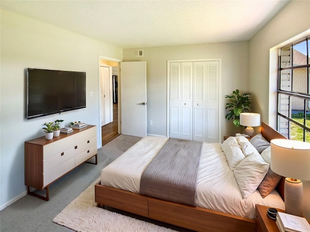 carpeted bedroom featuring a closet, multiple windows, and a textured ceiling