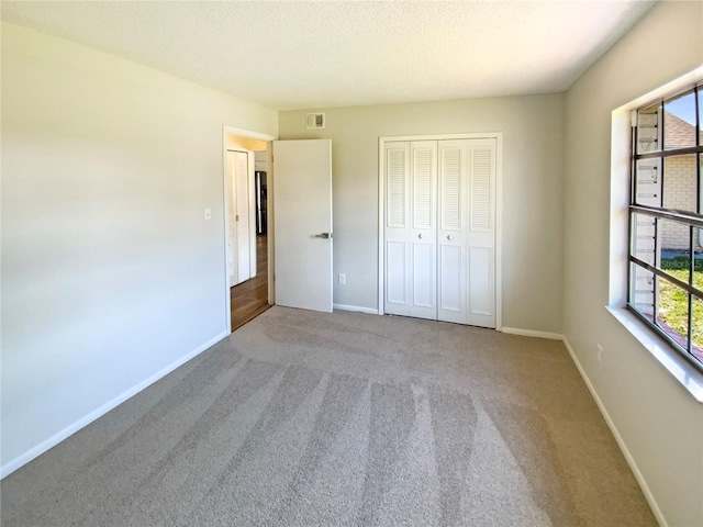 unfurnished bedroom featuring carpet flooring, a closet, and a textured ceiling