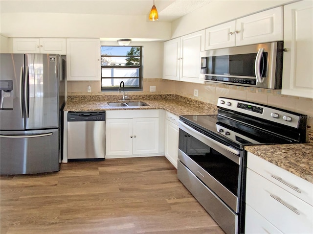 kitchen featuring stainless steel appliances, white cabinetry, light stone countertops, and sink