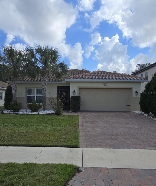 3869 Carrick Bnd, Kissimmee, FL 34746 - single story home with a front lawn, stucco siding, an attached garage, a tile roof, and decorative driveway