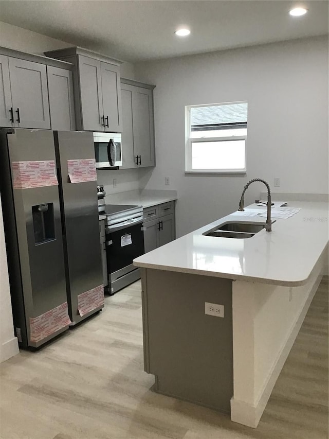 kitchen with sink, gray cabinets, appliances with stainless steel finishes, a kitchen breakfast bar, and kitchen peninsula