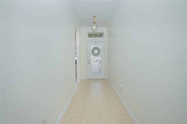 doorway to outside with light tile patterned floors and ornamental molding