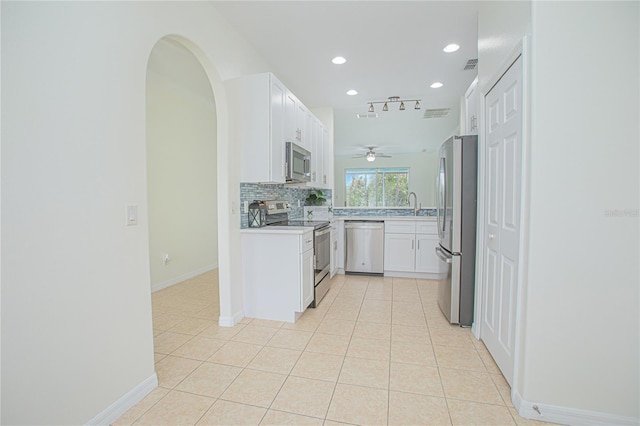 kitchen featuring sink, stainless steel appliances, tasteful backsplash, white cabinets, and light tile patterned flooring