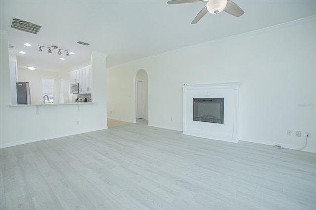 unfurnished living room featuring ornamental molding, sink, ceiling fan, and light hardwood / wood-style floors