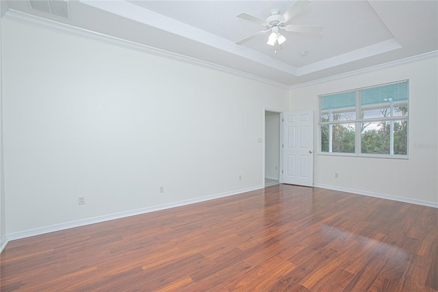 empty room featuring ceiling fan, dark hardwood / wood-style flooring, and a tray ceiling