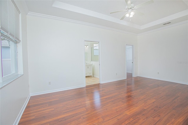 empty room featuring crown molding, a tray ceiling, and dark wood-type flooring