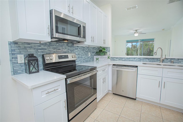 kitchen featuring sink, tasteful backsplash, light tile patterned floors, appliances with stainless steel finishes, and white cabinets