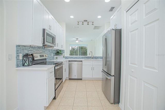 kitchen featuring sink, appliances with stainless steel finishes, white cabinetry, tasteful backsplash, and light tile patterned flooring