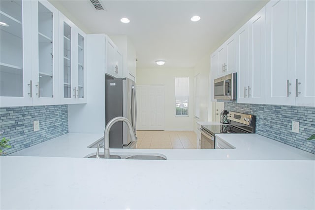 kitchen featuring sink, white cabinetry, light tile patterned floors, stainless steel appliances, and backsplash