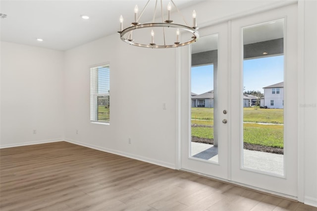 interior space featuring french doors, a notable chandelier, a wealth of natural light, and light wood-type flooring