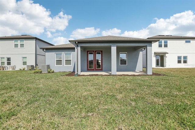 rear view of house with cooling unit, a patio area, and a lawn