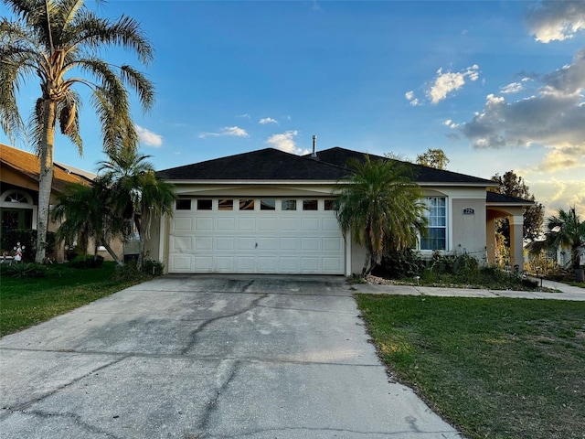 single story home featuring a garage and a front lawn