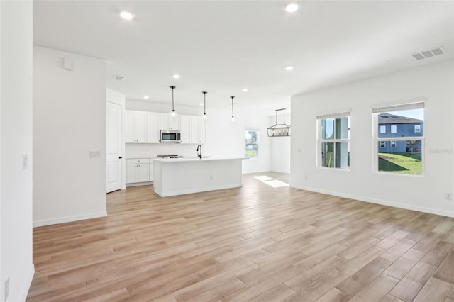 unfurnished living room with baseboards, light wood finished floors, visible vents, and recessed lighting