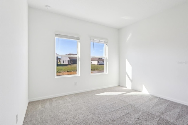 carpeted empty room featuring baseboards