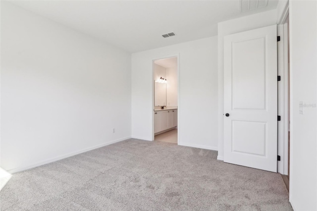 unfurnished bedroom featuring light carpet, ensuite bath, visible vents, and baseboards