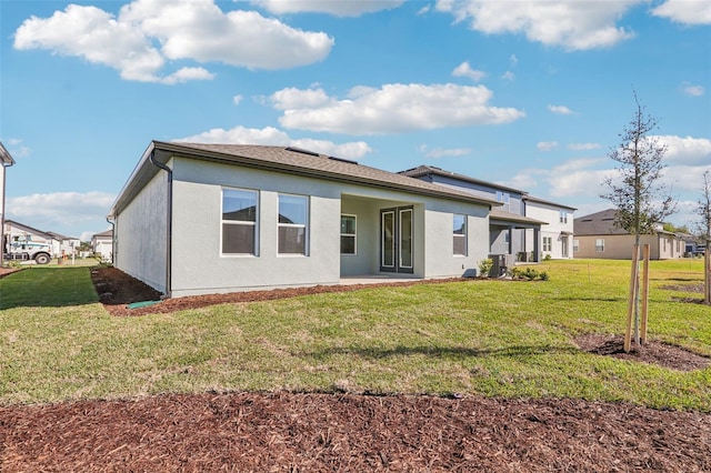 rear view of property featuring a yard, a patio, and stucco siding