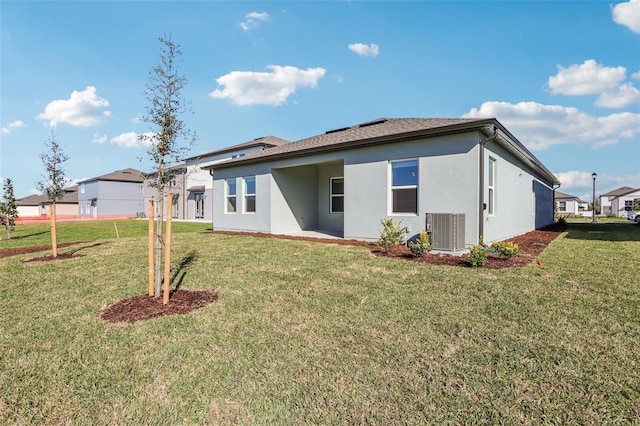 rear view of house with a patio, central AC unit, a lawn, and stucco siding