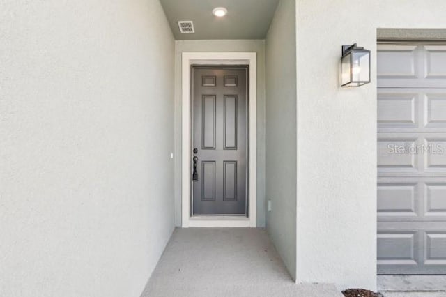 doorway to property featuring visible vents and stucco siding