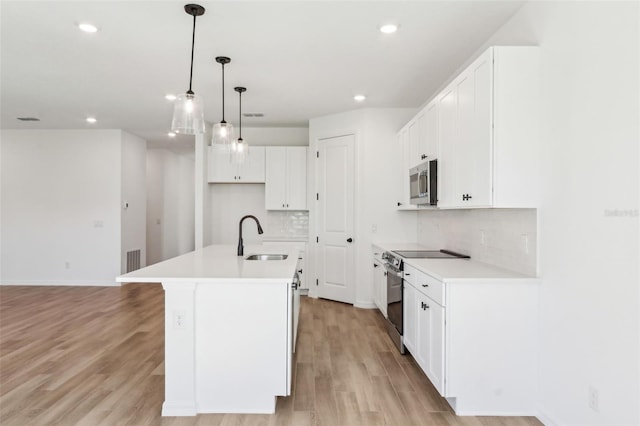 kitchen with stainless steel appliances, light wood-type flooring, a sink, and decorative backsplash