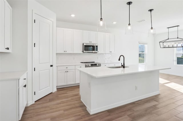 kitchen featuring light wood finished floors, visible vents, decorative backsplash, appliances with stainless steel finishes, and a sink