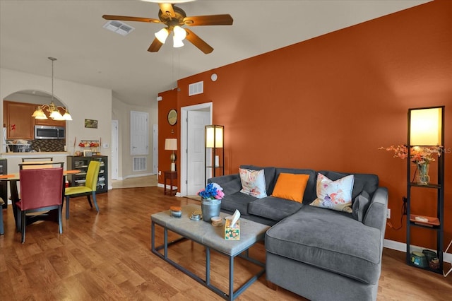 living area with light wood-style flooring, visible vents, and ceiling fan with notable chandelier