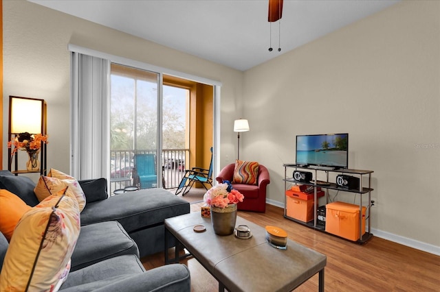 living area featuring ceiling fan, light wood-type flooring, and baseboards